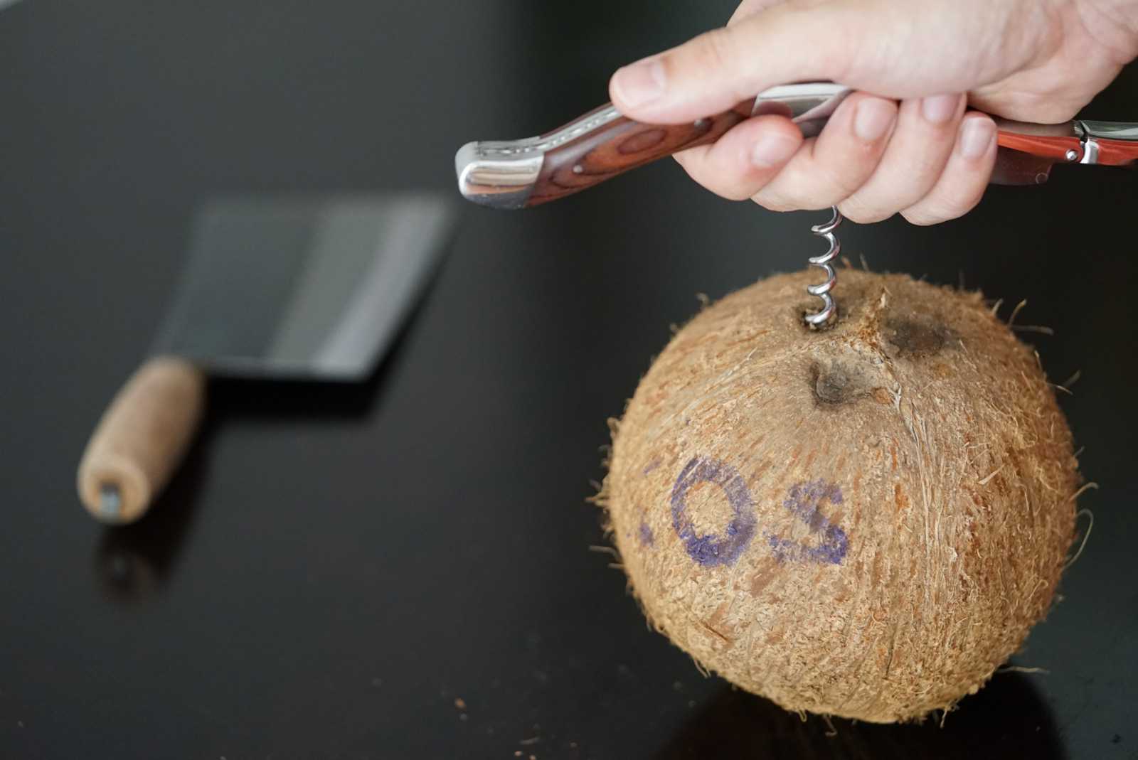 Poking coconut eyes with a corkscrew